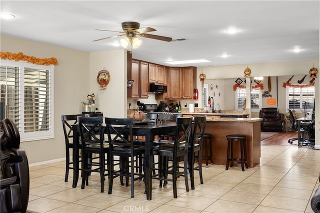 tiled dining room featuring ceiling fan, a healthy amount of sunlight, and sink