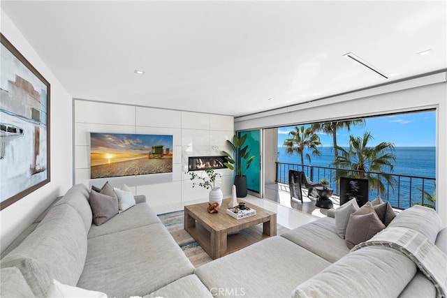 living room with wood-type flooring, a water view, and a tiled fireplace