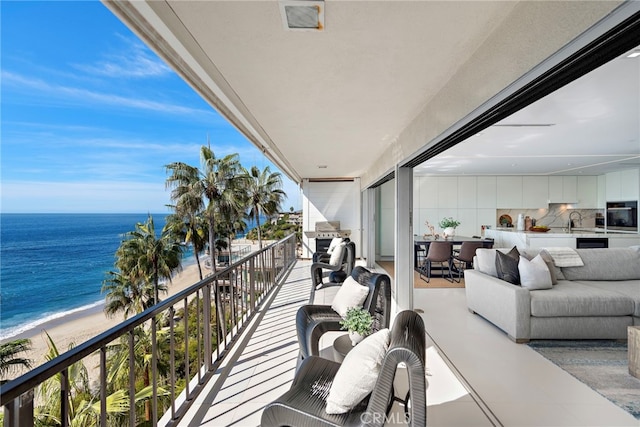 balcony with outdoor lounge area, sink, a water view, and a beach view