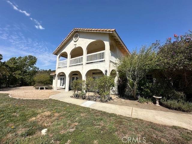 rear view of property featuring a balcony and a lawn