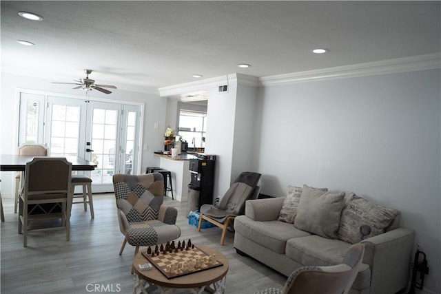 living room with light hardwood / wood-style floors, crown molding, french doors, and ceiling fan