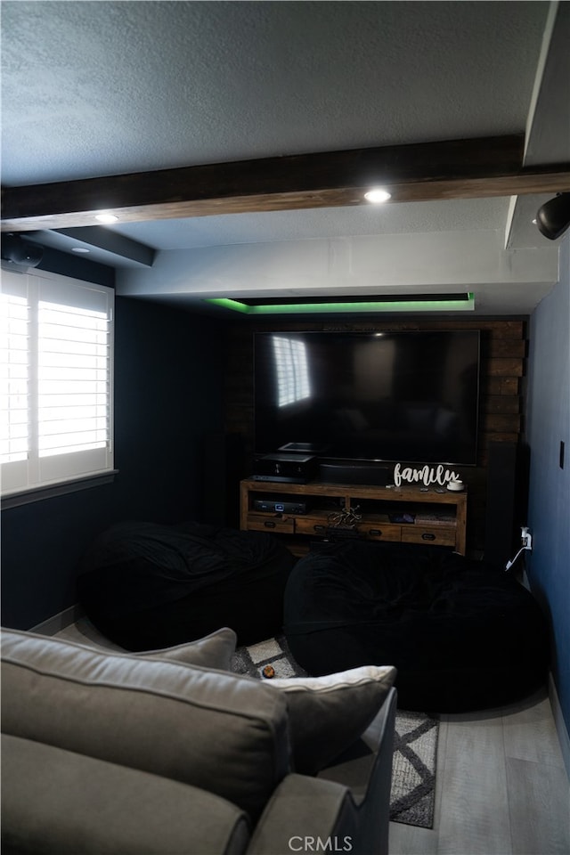 home theater with beam ceiling, hardwood / wood-style floors, and a textured ceiling