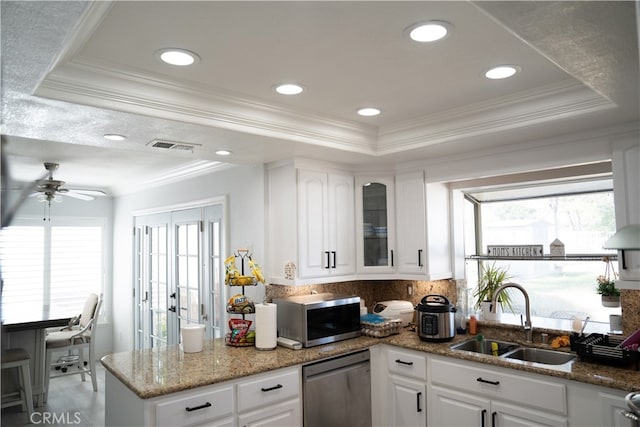 kitchen with sink, white cabinets, stainless steel appliances, and a tray ceiling