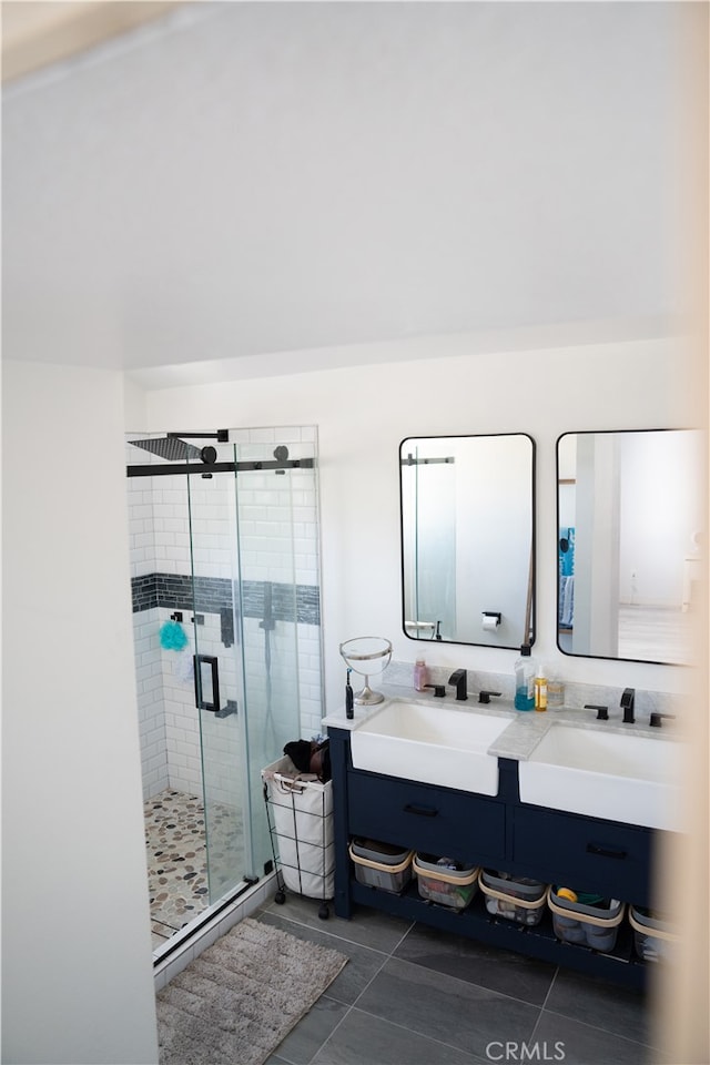 bathroom with a shower with door, vanity, and tile patterned floors