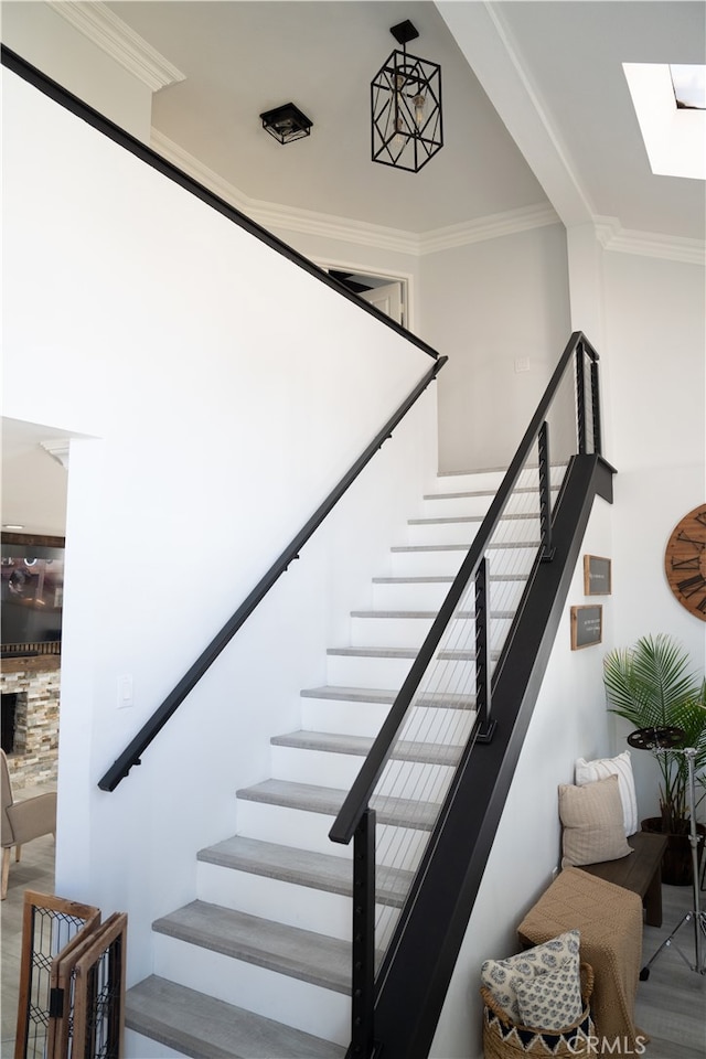 stairway featuring ornamental molding, hardwood / wood-style flooring, and a skylight