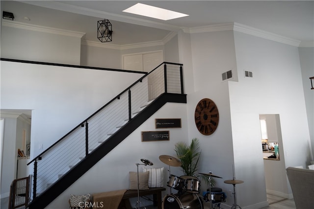 stairway featuring a towering ceiling and crown molding