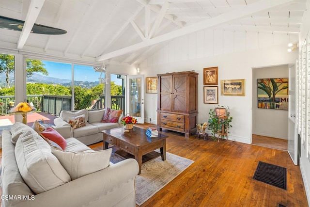 living room with beam ceiling, hardwood / wood-style floors, and high vaulted ceiling