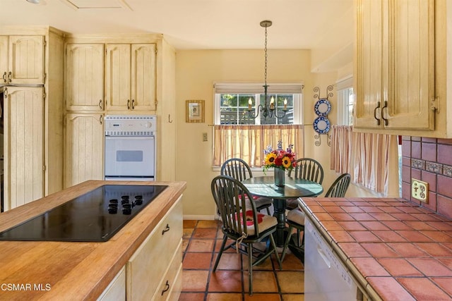 kitchen with decorative light fixtures, an inviting chandelier, tile countertops, white appliances, and dark tile patterned floors