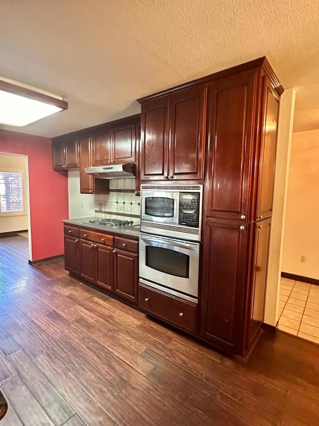 kitchen with decorative backsplash, appliances with stainless steel finishes, and dark hardwood / wood-style floors