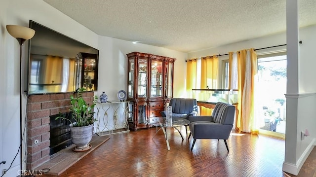 living area featuring a fireplace, a textured ceiling, and hardwood / wood-style flooring