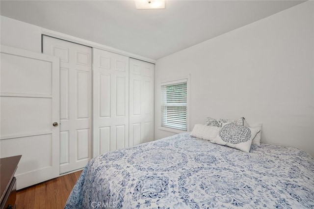 bedroom with dark hardwood / wood-style floors and a closet