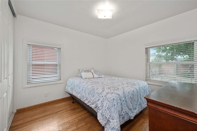 bedroom with multiple windows and hardwood / wood-style floors