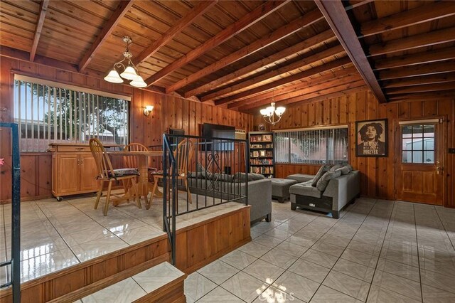 living room with wood walls, vaulted ceiling with beams, light tile patterned floors, wood ceiling, and a chandelier