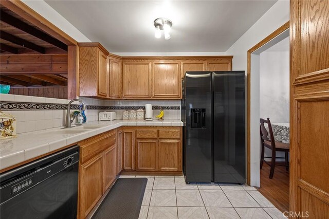 kitchen with backsplash, black appliances, sink, tile counters, and light tile patterned flooring