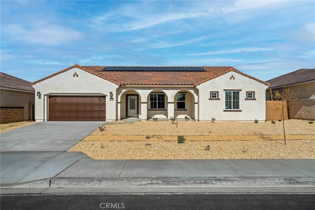 mediterranean / spanish-style home with a garage, a porch, and solar panels