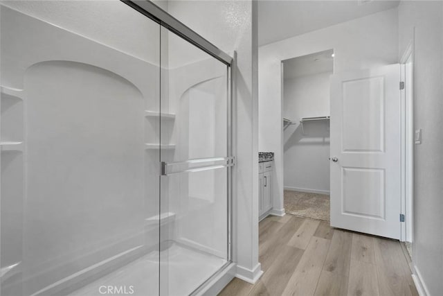 bathroom featuring walk in shower, vanity, and hardwood / wood-style flooring