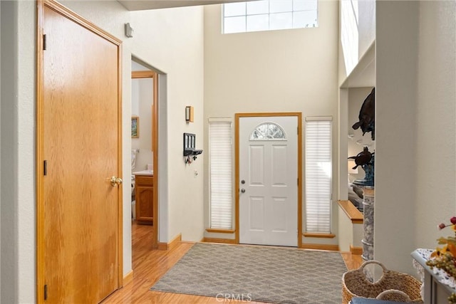 foyer entrance with a towering ceiling and light hardwood / wood-style floors