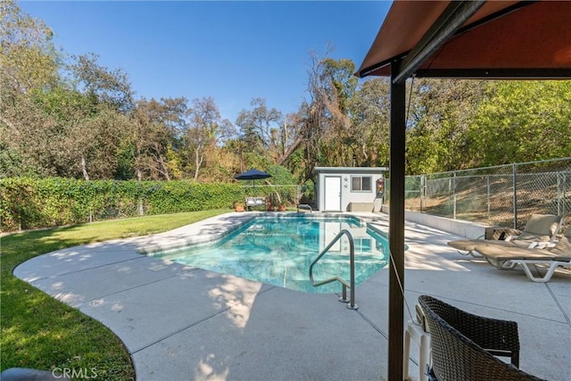 view of pool with a shed and a patio area