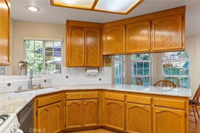 kitchen with white stove, sink, decorative backsplash, light hardwood / wood-style floors, and kitchen peninsula