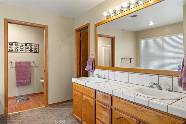 bathroom featuring hardwood / wood-style floors, vanity, and tasteful backsplash