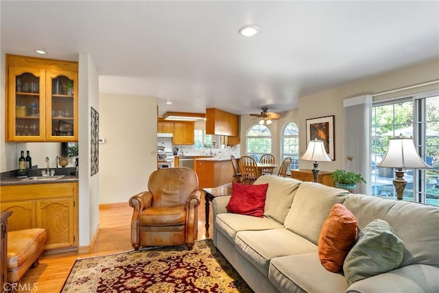 living room featuring ceiling fan, sink, and light hardwood / wood-style flooring