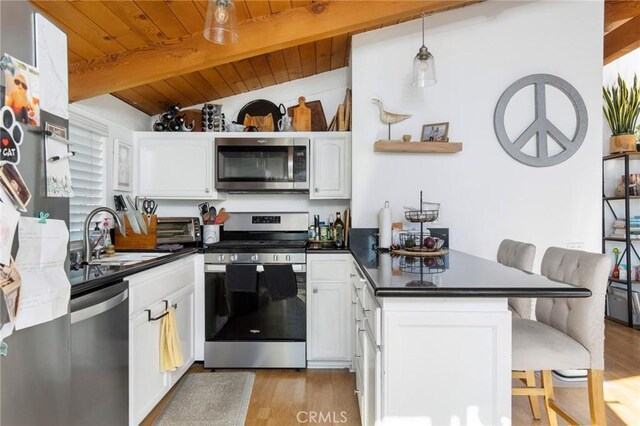 kitchen featuring a kitchen bar, sink, light wood-type flooring, stainless steel appliances, and white cabinets