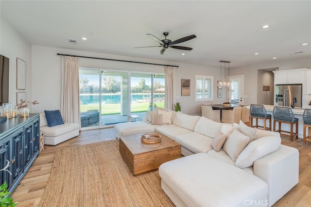 living room featuring light hardwood / wood-style flooring and ceiling fan with notable chandelier