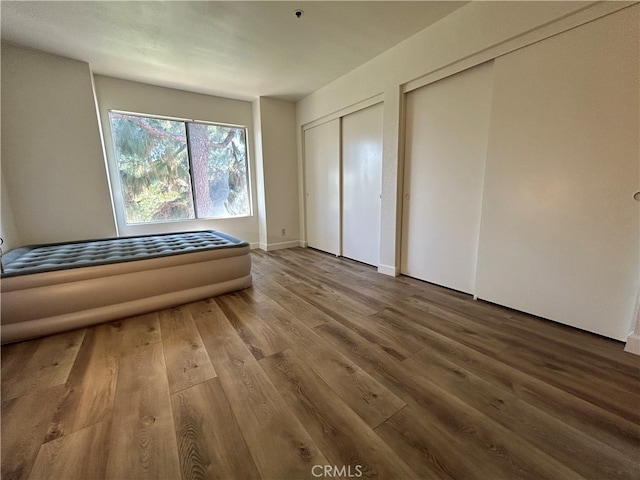 unfurnished bedroom with multiple closets and hardwood / wood-style floors