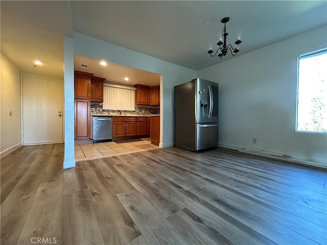 kitchen featuring tasteful backsplash, sink, light hardwood / wood-style floors, stainless steel appliances, and an inviting chandelier