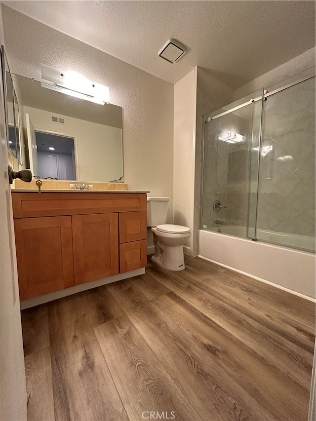 full bathroom with vanity, enclosed tub / shower combo, wood-type flooring, and toilet