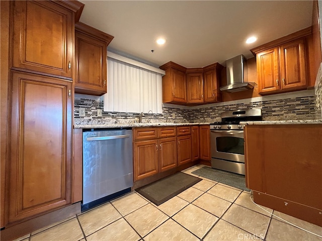 kitchen featuring wall chimney range hood, light stone counters, light tile patterned floors, backsplash, and stainless steel appliances