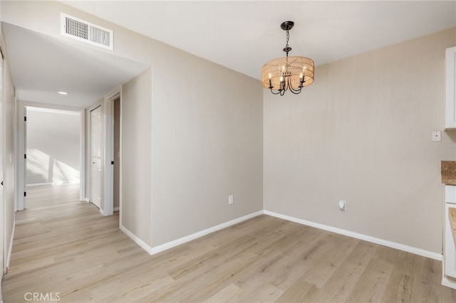 unfurnished dining area featuring light hardwood / wood-style flooring and an inviting chandelier