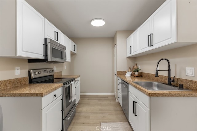 kitchen with stainless steel appliances, light hardwood / wood-style flooring, white cabinetry, and sink