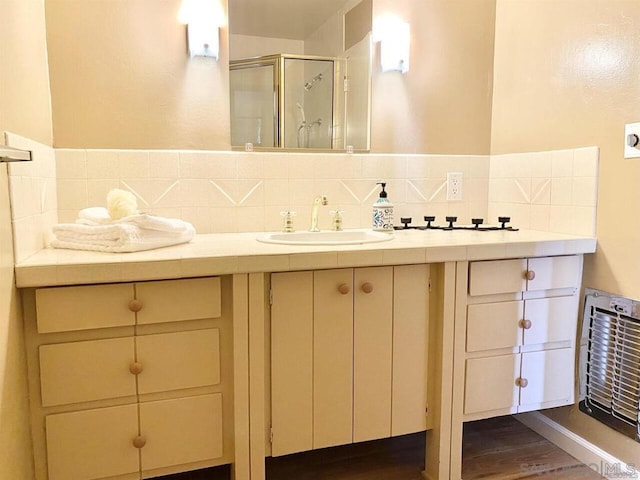 bathroom featuring vanity, a shower with door, and tasteful backsplash