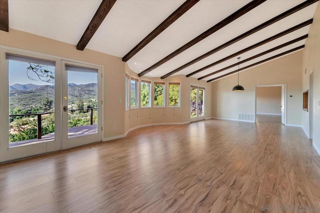 unfurnished living room with a mountain view, beam ceiling, and light wood-type flooring