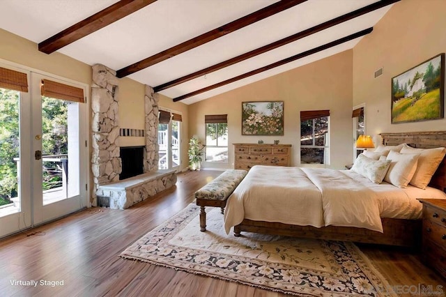 bedroom featuring access to exterior, a stone fireplace, hardwood / wood-style floors, and high vaulted ceiling