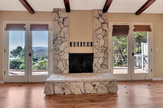 unfurnished living room featuring beamed ceiling, french doors, and a healthy amount of sunlight