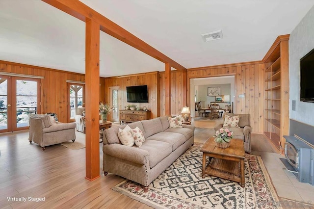 living room with light hardwood / wood-style floors, a wood stove, and wooden walls