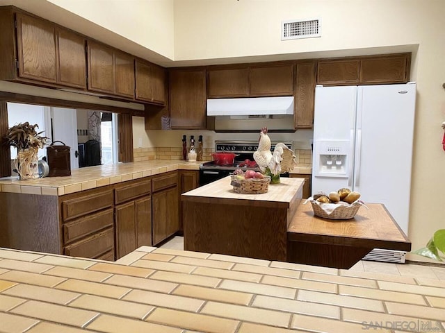 kitchen with white fridge with ice dispenser, dark brown cabinets, and stainless steel range with electric cooktop