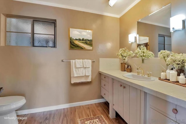 bathroom with wood-type flooring, vanity, tasteful backsplash, toilet, and ornamental molding