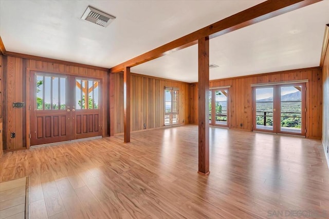 foyer entrance featuring french doors, wood walls, and light hardwood / wood-style floors