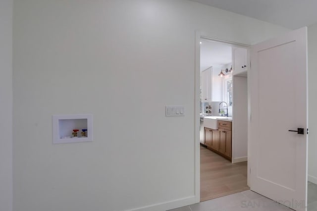 clothes washing area with sink, hookup for a washing machine, and light wood-type flooring