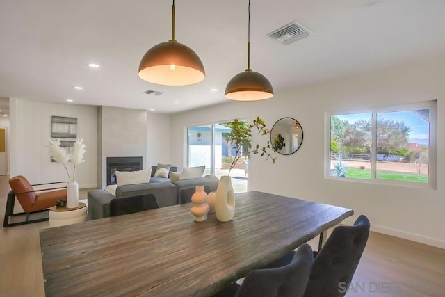 dining area with a tile fireplace, plenty of natural light, and hardwood / wood-style floors