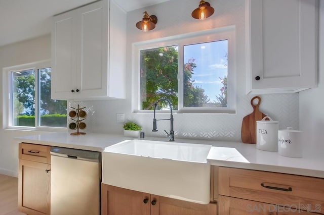 kitchen featuring white cabinets, tasteful backsplash, light hardwood / wood-style flooring, dishwasher, and sink