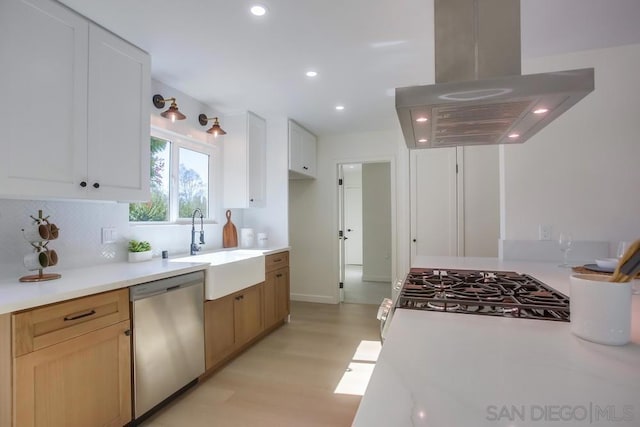 kitchen featuring sink, island exhaust hood, white cabinetry, and stainless steel appliances