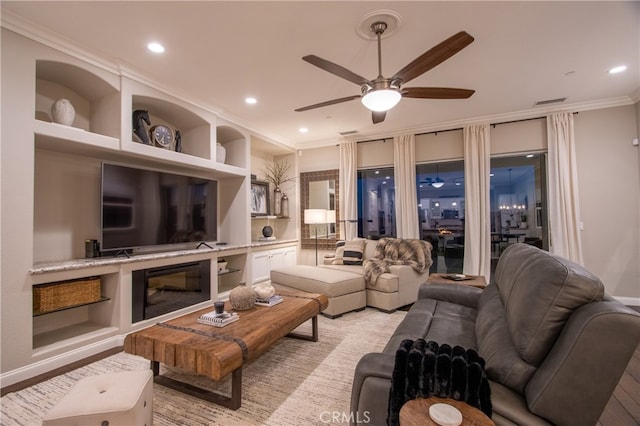 living room featuring light hardwood / wood-style floors, ornamental molding, ceiling fan, and built in shelves