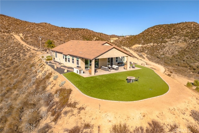 rear view of house with a yard, a patio area, a mountain view, and an outdoor hangout area