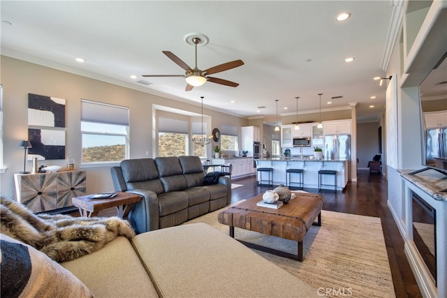 living room featuring crown molding, ceiling fan with notable chandelier, and dark hardwood / wood-style flooring