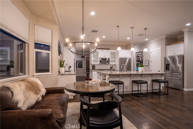 dining space with an inviting chandelier, ornamental molding, sink, and dark hardwood / wood-style flooring