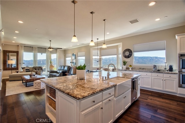 kitchen with a kitchen island with sink, a mountain view, sink, white cabinetry, and light stone counters